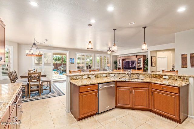 kitchen with light stone countertops, stainless steel dishwasher, sink, hanging light fixtures, and light tile patterned floors