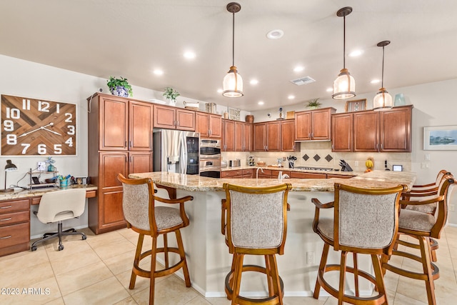 kitchen featuring stainless steel appliances, hanging light fixtures, a large island with sink, and a kitchen bar