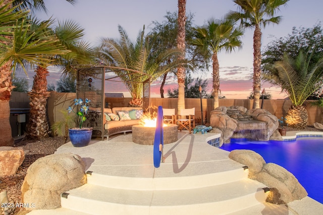 pool at dusk with a patio and pool water feature