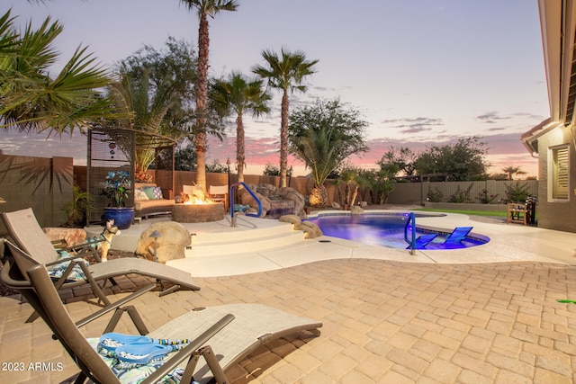 pool at dusk featuring an outdoor fire pit, pool water feature, and a patio area