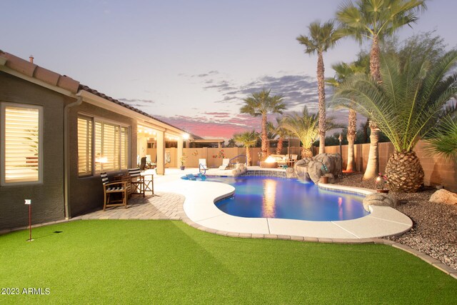 pool at dusk featuring a water slide and a patio area