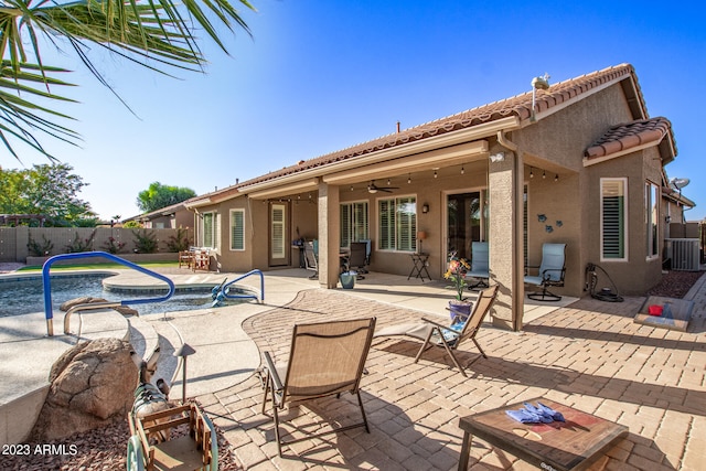 rear view of property featuring a fenced in pool, a patio, central AC unit, and ceiling fan