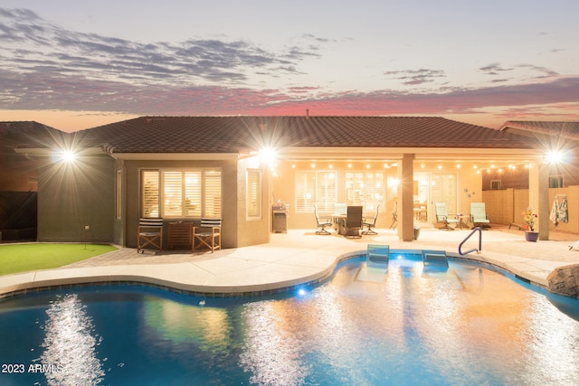 pool at dusk featuring a patio