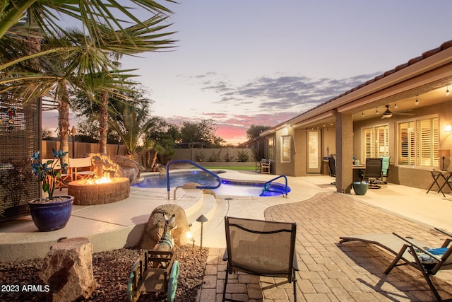 pool at dusk featuring an outdoor fire pit, a patio area, and ceiling fan