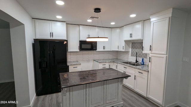 kitchen with dark stone counters, sink, black appliances, decorative light fixtures, and white cabinets