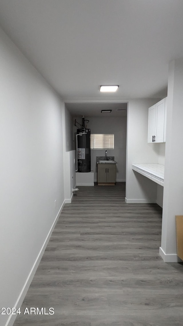 hall with sink, light hardwood / wood-style flooring, and water heater