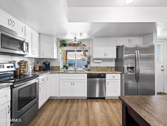 kitchen with dark stone counters, white cabinets, and appliances with stainless steel finishes