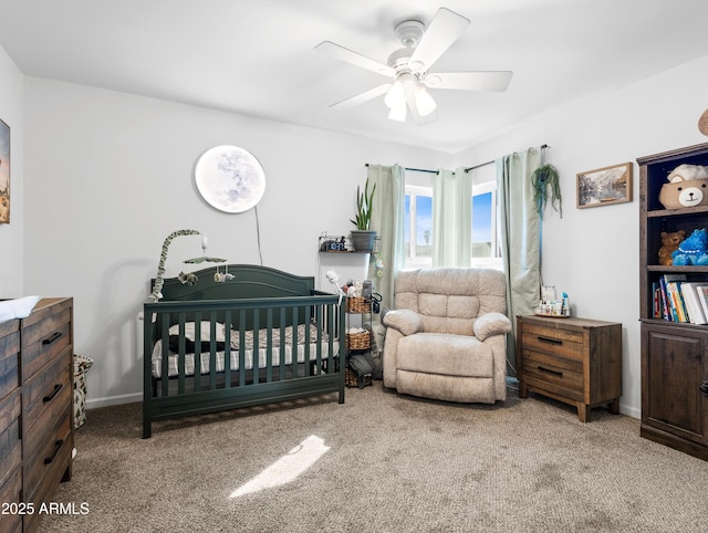 bedroom featuring a nursery area, ceiling fan, and carpet