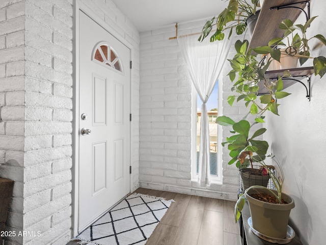 entryway featuring brick wall and hardwood / wood-style floors