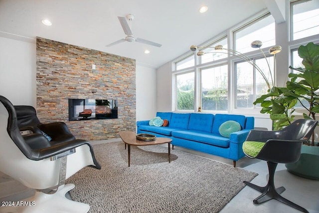 living room with a stone fireplace, plenty of natural light, lofted ceiling, and ceiling fan