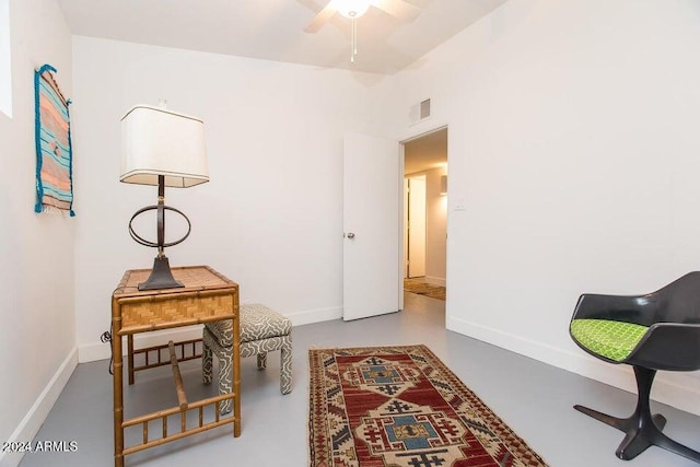 sitting room with ceiling fan and concrete floors