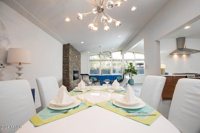 dining space with a fireplace, ceiling fan with notable chandelier, and vaulted ceiling