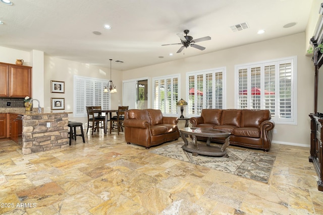 living room with ceiling fan with notable chandelier