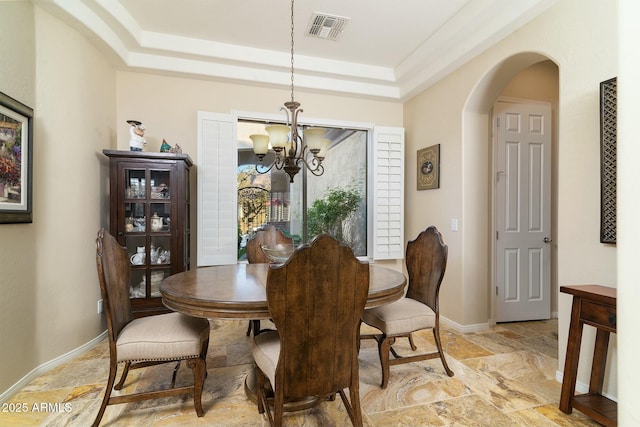 dining space with a notable chandelier and a raised ceiling