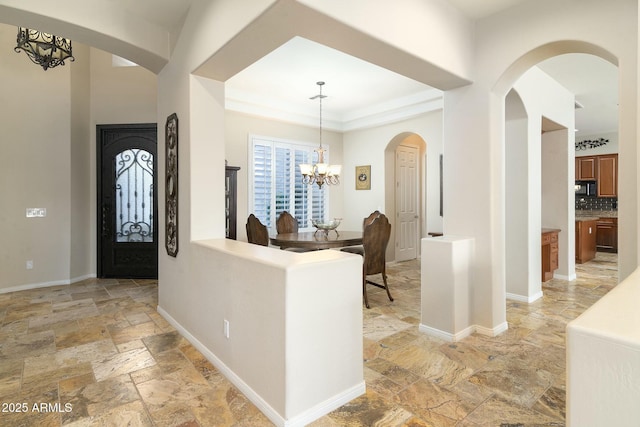 foyer entrance with a notable chandelier and a tray ceiling