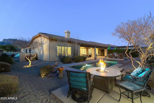 back house at dusk featuring an outdoor fire pit, a patio area, and a mountain view