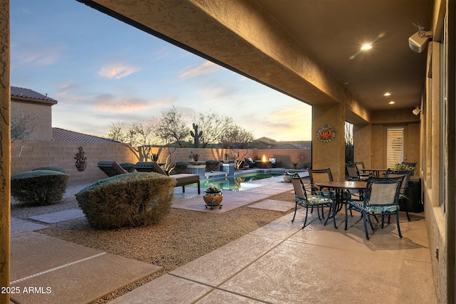 patio terrace at dusk with a fenced in pool