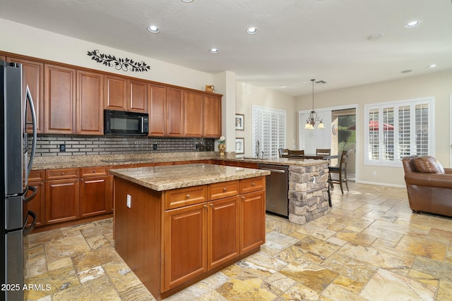 kitchen featuring light stone countertops, pendant lighting, a center island, stainless steel appliances, and a notable chandelier