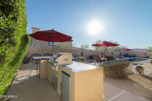 view of patio / terrace with exterior kitchen, exterior bar, a fenced in pool, and a grill