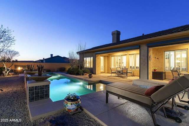 pool at dusk featuring a patio