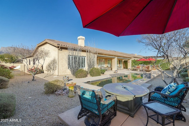 rear view of house featuring a patio area and a swimming pool with hot tub