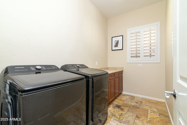 clothes washing area with washer and dryer and cabinets