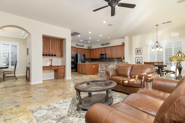 living room with sink and ceiling fan with notable chandelier