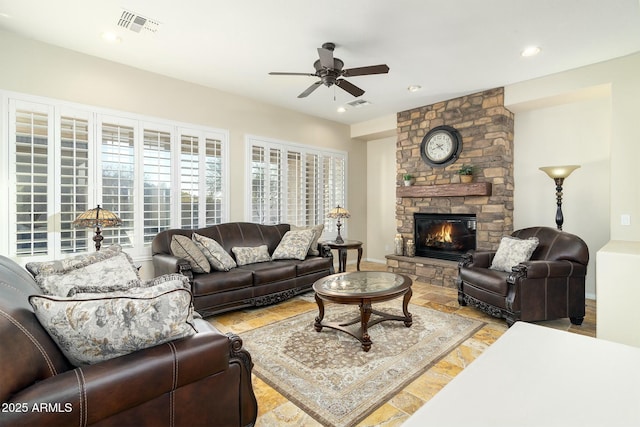 living room with ceiling fan and a stone fireplace