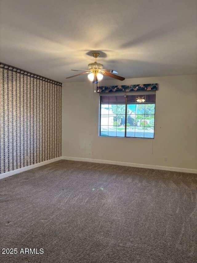 carpeted spare room featuring ceiling fan and baseboards