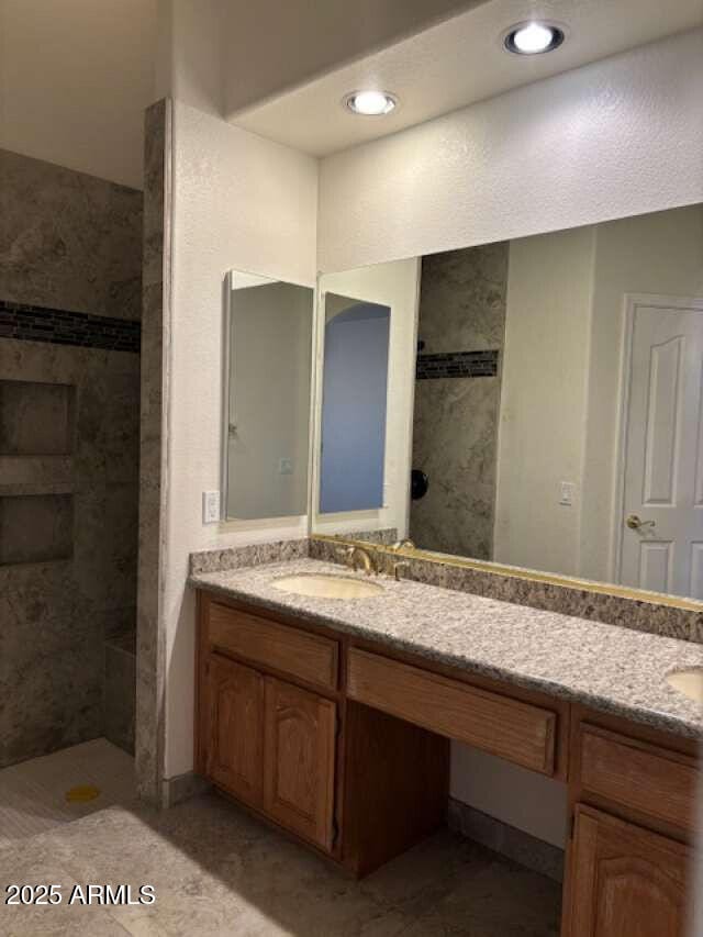 full bathroom with double vanity and tiled shower