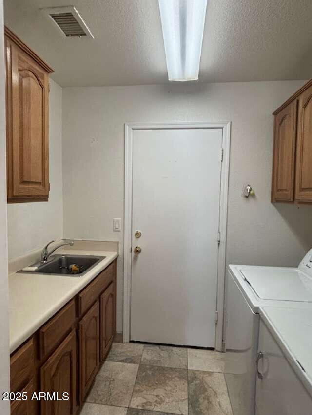 washroom with cabinet space, washer and clothes dryer, and a textured ceiling