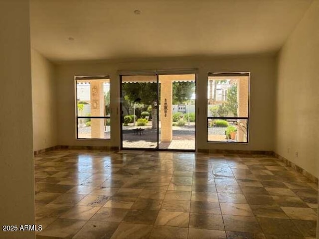 unfurnished room featuring plenty of natural light and baseboards