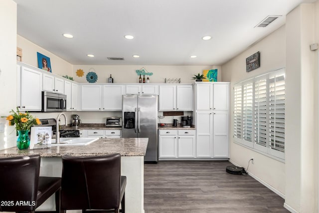 kitchen featuring appliances with stainless steel finishes, recessed lighting, white cabinets, a peninsula, and dark wood-style flooring
