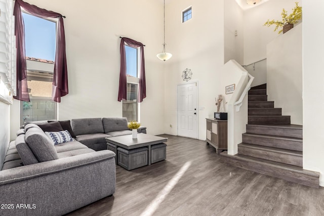 living room featuring wood finished floors, stairway, and a towering ceiling