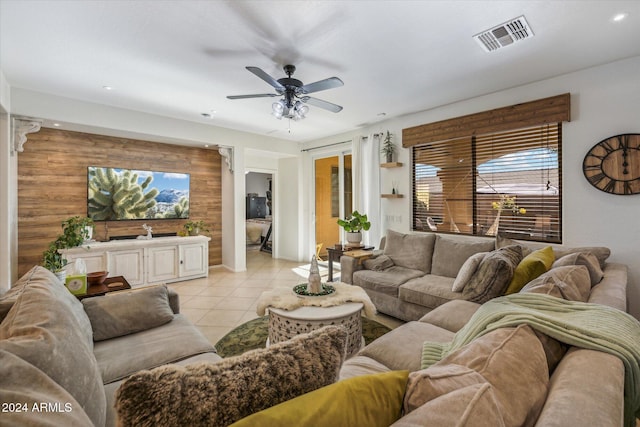 living room featuring ceiling fan, wood walls, and light tile patterned floors