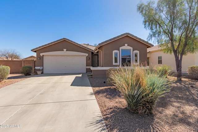 view of front of house featuring an attached garage, fence, concrete driveway, a tiled roof, and stucco siding