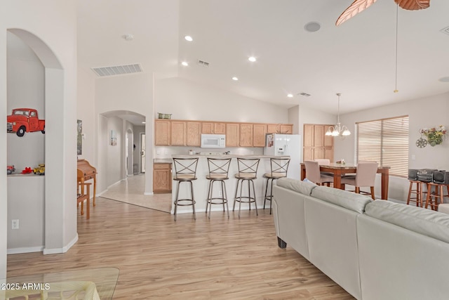 living room with visible vents, arched walkways, light wood-style flooring, high vaulted ceiling, and recessed lighting