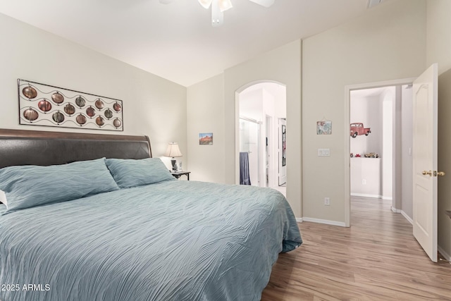 bedroom featuring arched walkways, ceiling fan, baseboards, and wood finished floors