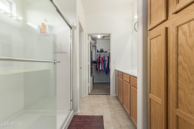 full bath featuring a spacious closet, a shower stall, and vanity