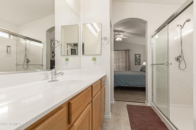 ensuite bathroom with ceiling fan, connected bathroom, vanity, vaulted ceiling, and a shower stall