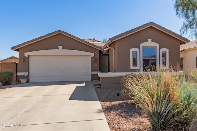 ranch-style house with a garage, a tiled roof, concrete driveway, and stucco siding