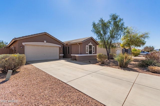 ranch-style home featuring driveway, an attached garage, a tiled roof, and stucco siding