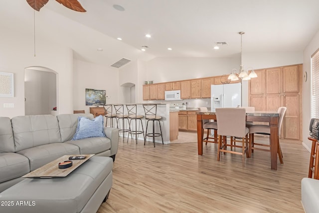 living area with arched walkways, visible vents, and light wood finished floors