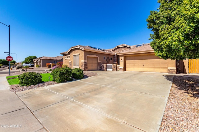 view of front of property featuring stucco siding, stone siding, roof mounted solar panels, and concrete driveway