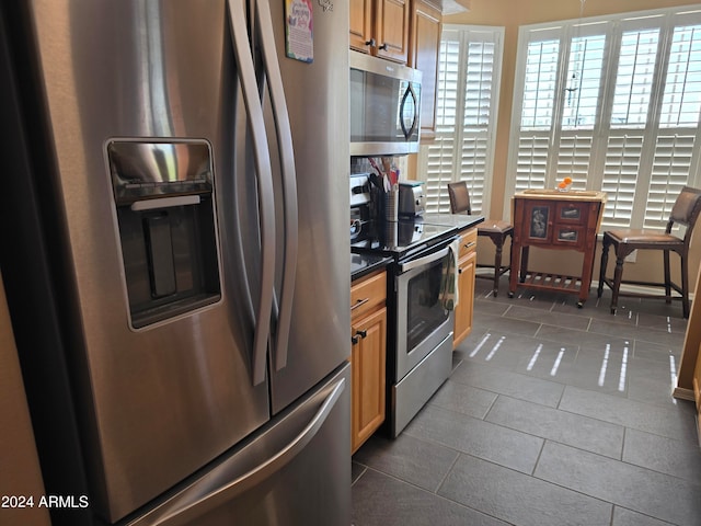 kitchen featuring dark tile flooring and appliances with stainless steel finishes