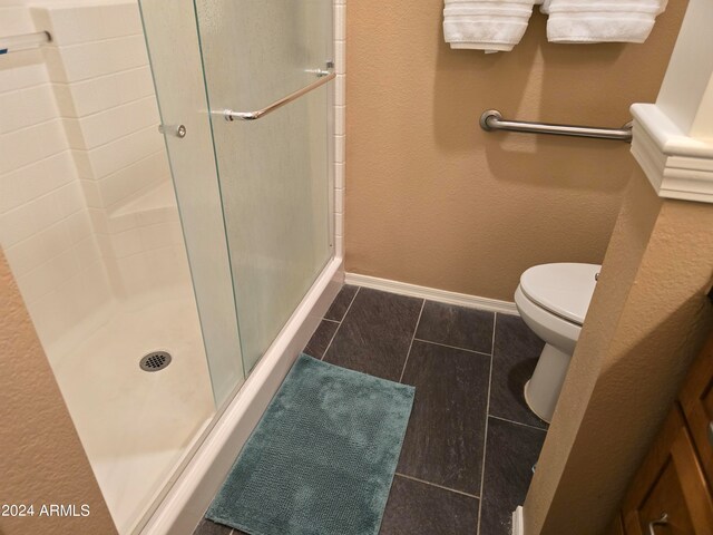 bathroom featuring a shower with door, tile floors, and toilet