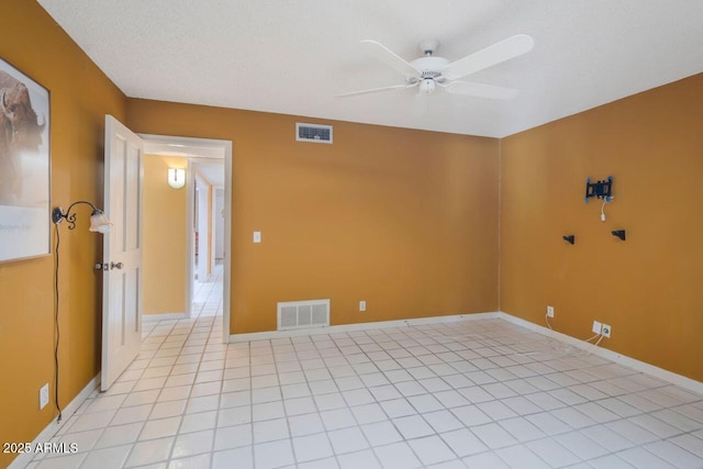 empty room with light tile patterned floors, visible vents, baseboards, and a ceiling fan