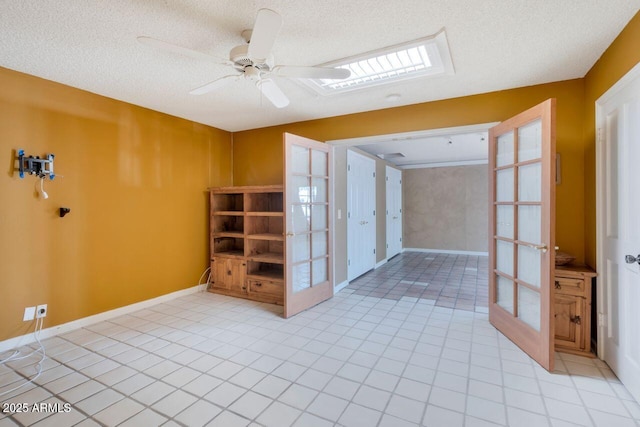 empty room with a textured ceiling, french doors, light tile patterned floors, baseboards, and ceiling fan