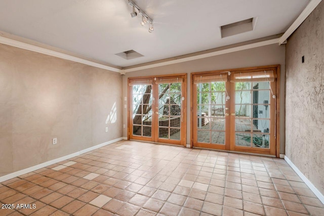 empty room featuring track lighting, french doors, baseboards, and ornamental molding