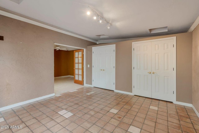 unfurnished bedroom with crown molding, light tile patterned floors, a textured wall, and baseboards